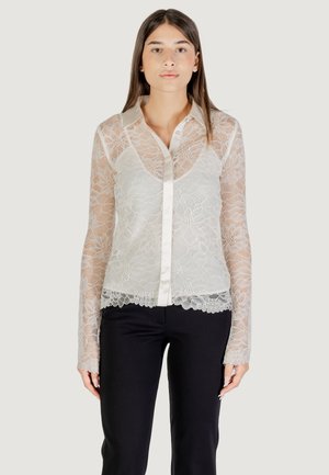 Blouse en dentelle à manches longues, couleur crème clair, fermeture à boutons sur le devant, col en satin et motifs floraux à l'ourlet et aux manches.