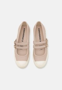 Zapatillas de slip-on de color rosa claro con dos correas de hebilla, suelas de goma y una punta blanca. Material suave con una forma redondeada.