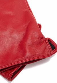 Czerwone skórzane rękawiczki o gładkiej fakturze, z klapą i czarnym ozdobnym przeszyciem. W części dłoniowej znajduje się małe wycięcie.