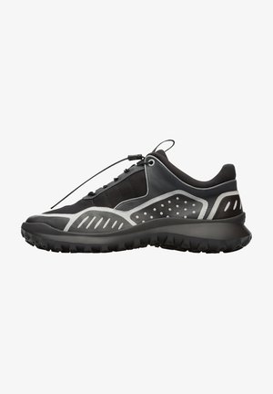 Chaussure de sport noire et grise avec une tige texturée, un système de lacets élastiques et une semelle robuste multidirectionnelle. Comprend des perforations et des accents.