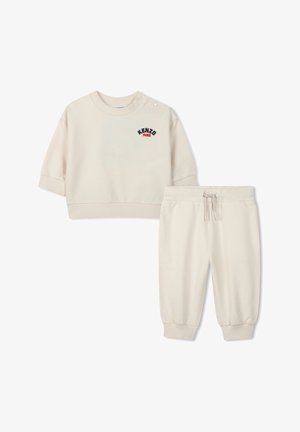 Felpa color crema con maniche corte e chiusura a bottoni, con la scritta "KENZO PARIS" ricamata. Pantaloni jogger abbinati con vita elastica.