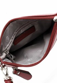 Rød lædertaske indvendigt med en grå stofforing, der har et subtilt logomønster, lynlåslomme og metalhardware detaljer.