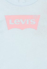 Ανοιχτό μπλε βαμβακερό t-shirt με ροζ λογότυπο της Levi's σε αντίθετη λευκή γραμματοσειρά μέσα σε σχέδιο κυκλικής πινακίδας.