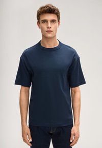 Granatowy bawełniany t-shirt z krótkimi rękawami, okrągłym dekoltem i luźnym krojem. Bez widocznych wzorów ani akcentów.