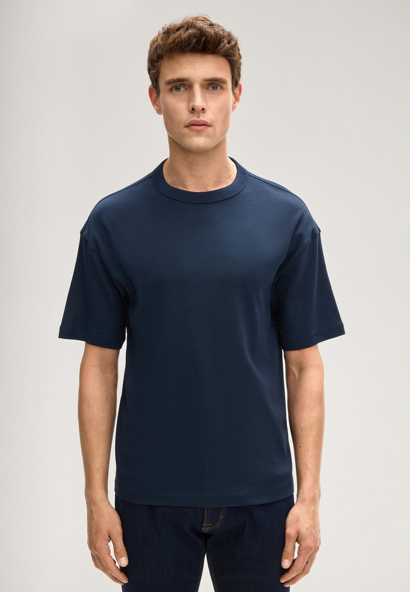 Granatowy bawełniany t-shirt z krótkimi rękawami, okrągłym dekoltem i luźnym krojem. Bez widocznych wzorów ani akcentów.