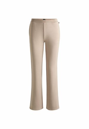 Pantaloni a zampa d'elefante beige realizzati in morbido tessuto elasticizzato. Caratterizzati da una vita liscia e senza chiusure o tasche visibili.