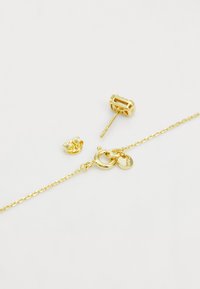 Guld smykke sæt inklusive en kædearmbånd med en rund lås og to studs øreringe med teksturerede designs og en klar sten accent.