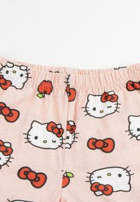 Light pink cotton shorts with an elastic waistband featuring a repeated pattern of Hello Kitty faces, red bows, and red apples.