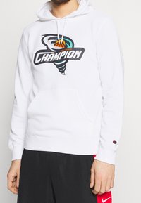 Vit hoodie med en grafisk logotyp som har en tornadodesign och basketelement, tillverkad av mjukt tyg med en framficka.