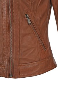 Veste en cuir marron avec une poche zippée et une finition texturée. Couture texturée le long des coutures et détail de taille ajustée.