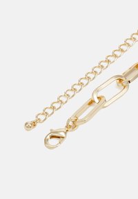 Bracciale in oro con elementi ovali e rotondi collegati, finitura testurizzata e chiusura con moschettone dotata di un piccolo accento sferico.