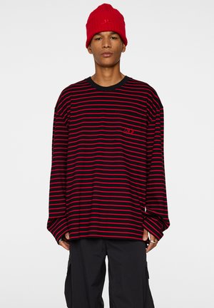 Langärmliges schwarz-rotes gestreiftes Shirt mit rundem Halsausschnitt, das ein kleines Logo auf der Brust und weit geschnittene Ärmel aufweist.