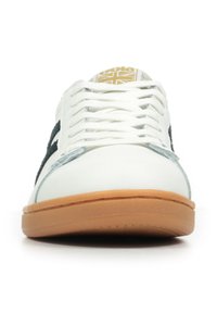 Sneaker bianca con accenti verde scuro, suola in gomma, pannelli laterali texture e logo dorato sulla linguetta. Caratterizzata da un design di allacciatura standard e una finitura liscia.