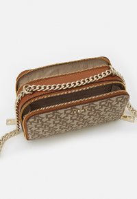 Brązowa skórzana torba na zamek z teksturowanym płótnem, złotymi okuciami, łańcuszkowym paskiem i przymocowanym logo. Posiada wiele przegródek.