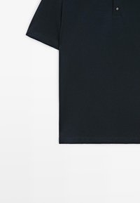 Schwarzes Polohemd mit kurzen Ärmeln und strukturierter Stoffqualität, ausgestattet mit einer Knopfleiste mit zwei Knöpfen und einem geraden Saum vor weißem Hintergrund.