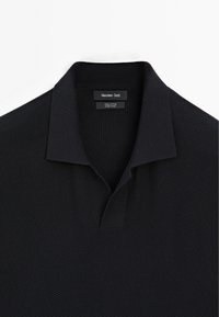 Polo shirt in cotone nero con un motivo testurizzato, un classico colletto a piatto e una chiusura a due bottoni. Etichetta del marchio visibile all'interno.