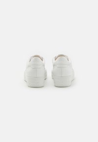 Weiße Sneaker mit einem glatten Lederoberteil, abgerundeter Zehenpartie, gepolstertem Kragen und strukturiertem Gummisole. Dezentes Branding an der Ferse.