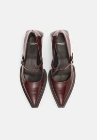 Burgundy leather pointed-toe shoes with a mid-height block heel, featuring a Mary Jane strap and smooth black interior lining.