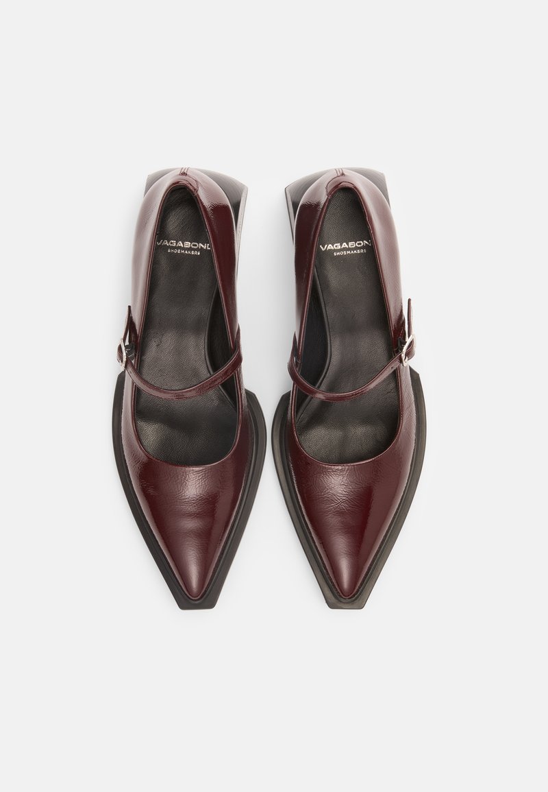 Mary Jane in pelle verniciata color bordeaux con punta affusolata, cinturino alla caviglia e tacco spesso nero. Texture liscia con hardware minimale.