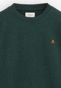 Sudadera de color verde oscuro hecha de algodón, con un cuello redondo y un logo de calavera y huesos cruzados en naranja en el pecho.