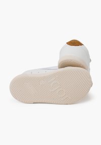 Weiße Schuhe mit strukturierten Gummisohlen und einem beigefarbenen Lederakzent an der Ferse. Rundliche Zehenform und minimalistisches Design.