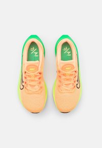 Une paire de chaussures de course Nike Zoom Fly 5 en pêche avec un swoosh noir et une semelle vert fluo, vue de dessus sur un fond blanc.