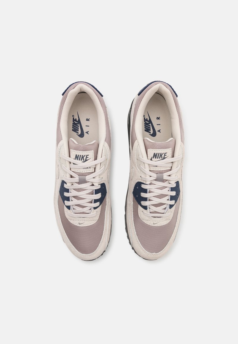 Nike Air Sneaker mit einem hellgrauen und navyfarbenen Farbschema, Obermaterial aus Netzgewebe, gepolstertem Kragen und kontrastierender Gummisohle.