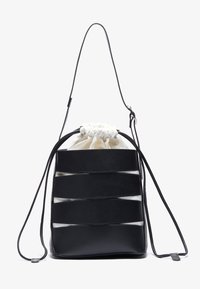 Mustaa nahkainen nyörilaukku, jossa on vaaleanruskea kangasisus, vaakasuorat leikkuureijät ja yksi säädettävä hihna. Sileä pinta.