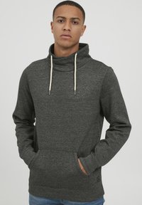 Mørkegrå pullover hættebluse lavet af struktureret stof. Har højt krave, snoretræk og forlommer med ribstrikkede manchetter og kant.