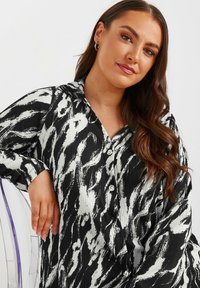 Camicia a maniche lunghe a righe bianche e nere, con tessuto testurizzato, colletto e bottoni sul davanti, dal taglio morbido.