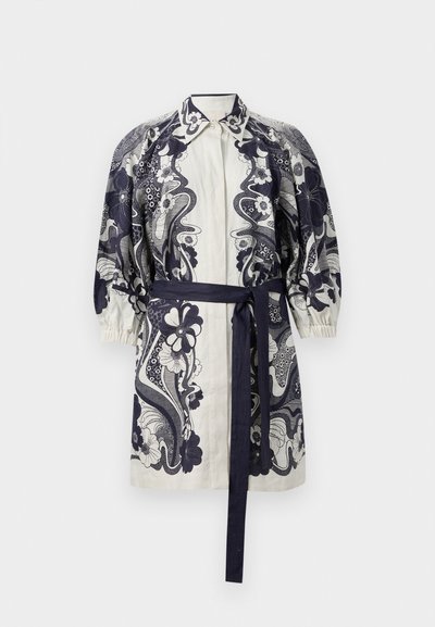 Kreminė marškinių suknelė su tamsiai mėlynais gėlių raštais, su apykakle, pūstomis rankovėmis ir atitinkamu juosmens diržu, pagaminta iš lengvos medžiagos.