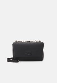 Svart rektangulär handväska med ribbad textur, rem av metallkedja och en logotypmärket framtill. Har en viks över klaffstängning.