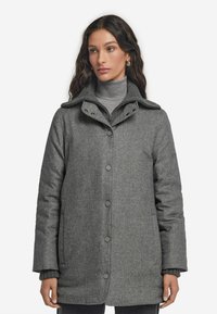 Grå ullkappa med knappframsida och hög krage. Har stora knappar och sidofickor, med ett mjukt, texturerat tyg.