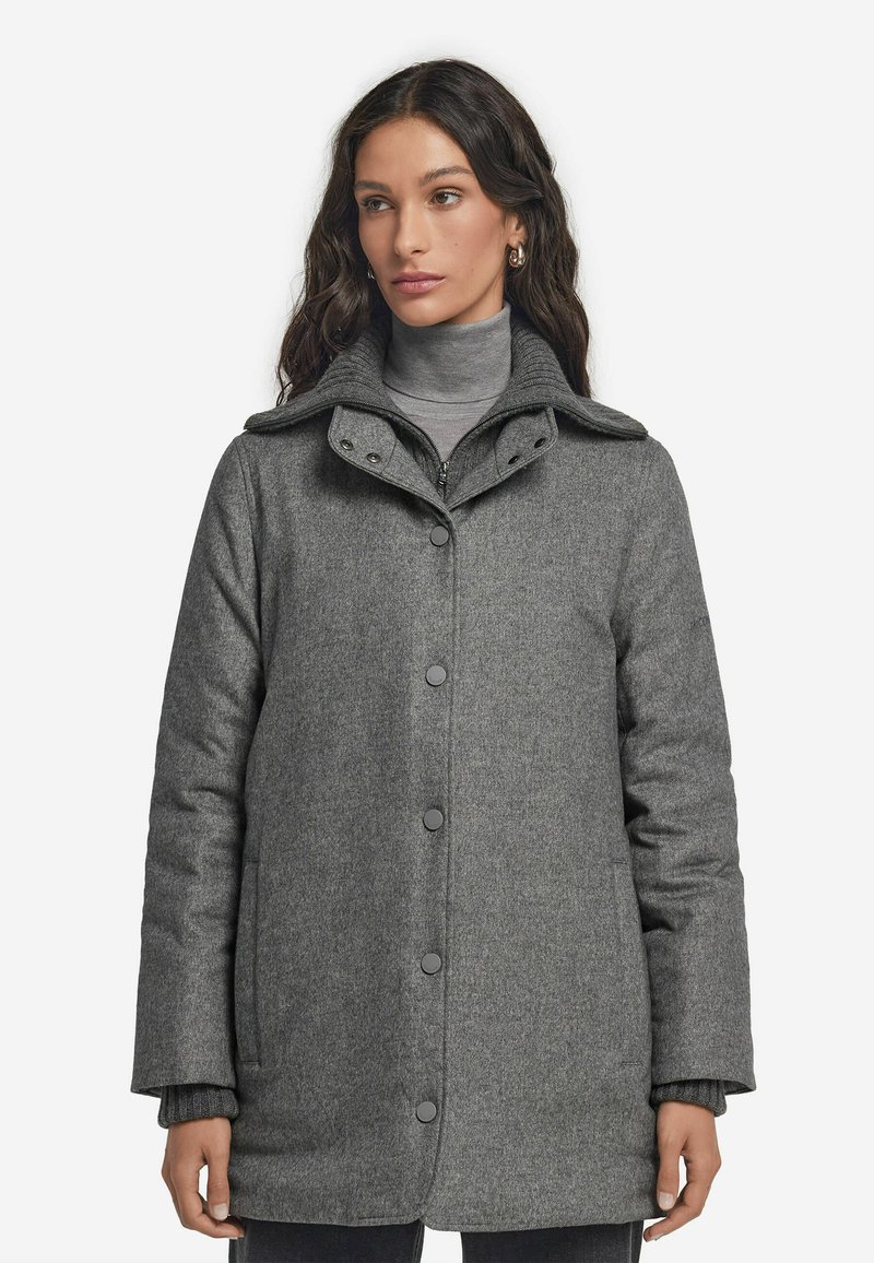 Grå ullkappa med knappframsida och hög krage. Har stora knappar och sidofickor, med ett mjukt, texturerat tyg.