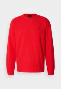 Pull rouge à col rond avec manches longues et petit logo noir "BOSS" sur le côté gauche de la poitrine.