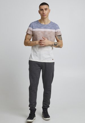 Short-sleeve, crew-neck shirt with horizontal stripes in blue, brown, and white, paired with textured black pants and black sneakers.