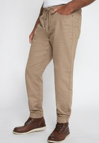 Beige joggerbroeken van katoenmix, met een elastische tailleband, trekkoord, zijzakken en taps toelopende boorden. Draag ze met bruine laarzen.