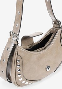 Bolso de mano de imitación cuero beige con tachuelas plateadas, de forma redondeada, correa ajustable y un compartimento con cremallera. Acabado texturizado con acentos negros.