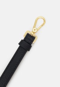 Cinturino in pelle nera con una clip in metallo dorato, che presenta una superficie testurizzata e un'asola in pelle regolabile vicino alla clip.