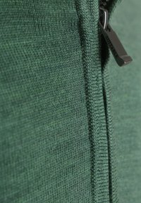 Groen gebreide stof met een close-up van een ritslip met de ingekraste tekst "SUITABLE."