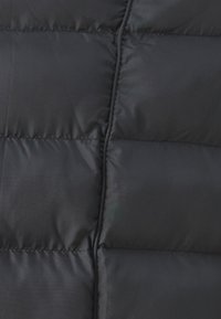 Puffer bunda s prešívaným dizajnom, vyrobená z hladkej čiernej látky, s horizontálnymi sekciami a jemným leskom. Viditeľné švy.
