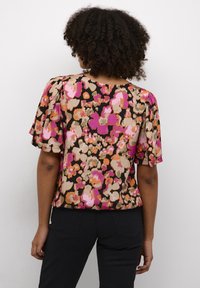 Blusa a maniche corte con un motivo floreale multicolore su sfondo nero, realizzata in tessuto leggero e dalla vestibilità rilassata.