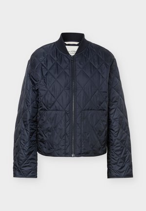 Granatowa pikowana kurtka z przeszyciami w kształcie diamentów, przednim zamkiem błyskawicznym, prążkowanym kołnierzem i dwoma kieszeniami z przodu na jednolitym tle.