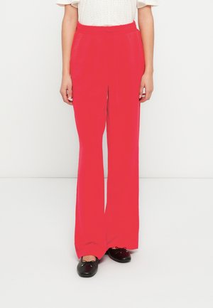 Rote Schlaghosen mit strukturierter Oberfläche und elastischem Bund, kombiniert mit schwarzen flachen Schuhen. Einfaches Design, geeignet für legere Kleidung.