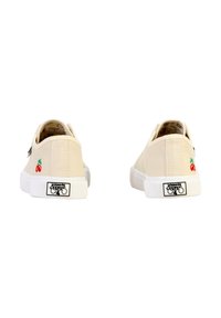 Zapatillas de lona en beige con suelas de goma blanca, con bordado de cerezas rojas en los laterales y un logo en el talón.