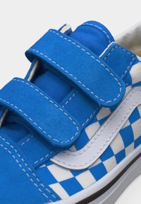 Μπλε και άσπρο αθλητικό παπούτσι με καρό σχέδιο, δύο φαρδιές μπλε λουριά Velcro και άσπρη κυματιστή ρίγα στο πλάι με ραφές λεπτομέρειες.