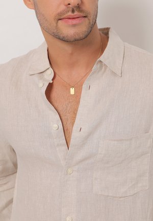 Light beige linen shirt with a relaxed fit, button-down collar, pocket on the left chest, and a gold pendant necklace.