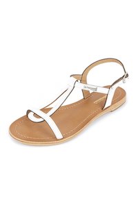 Witte leren sandaal met een T-bandenontwerp, platte zool en een bruine binnenzool. Voorzien van een gesp voor aanpassing en accentuerende stiksels.