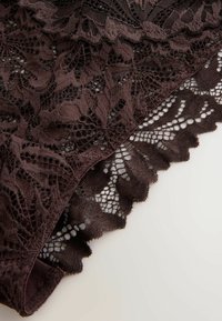 Dunkelbrauner Spitzenstoff mit Blumenmustern und gewellten Rändern auf hellem Hintergrund, der detaillierte Textur und filigranes Design zeigt.