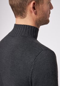 Dunkelgrauer Strickpullover mit hohem geripptem Kragen. Die Stoffstruktur wirkt glatt, mit enganliegenden Ärmeln und Schulternaht.